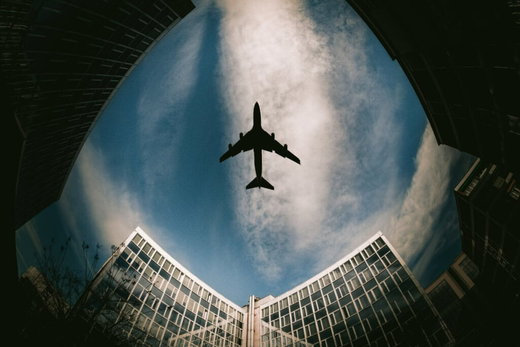 airplane-flying-over-city-buildings-on-cloudy-day-2026-03-18-16-04-24-utc (1)