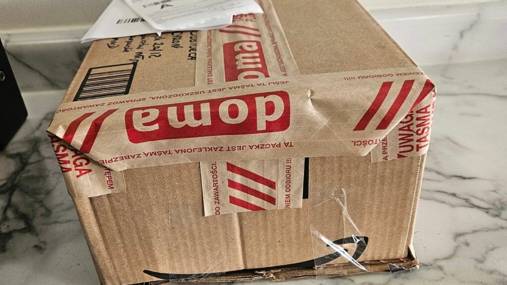 A cardboard box with red and white warning tape, and a shipping label.