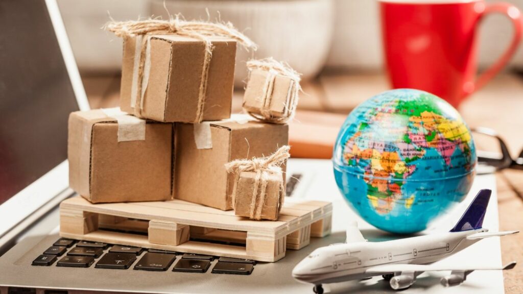 Small packages on a pallet on a laptop with a globe and airplane.