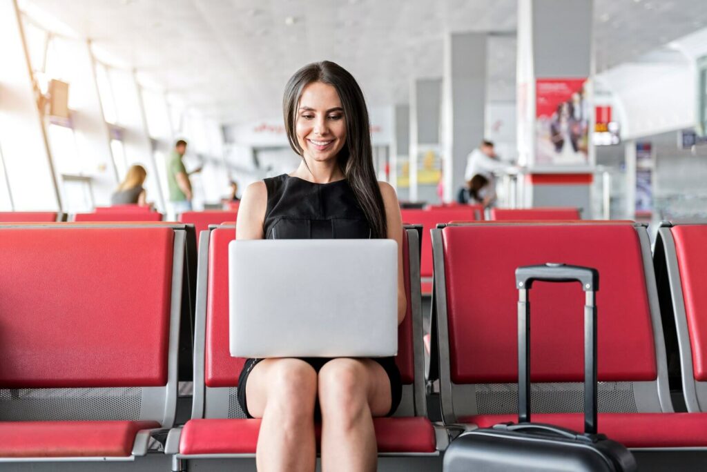 smiling-woman-works-on-laptop-in-airport-lounge-2026-04-13-00-36-49-utc (1)